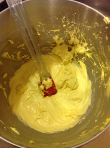 a metal bowl containing yellow batter for Geneva Wafers. There's a red plastic spatula in the bowl